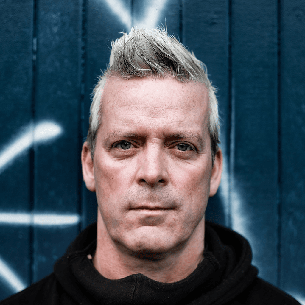 Portrait of Sean Cranbury against a blue wooden wall.